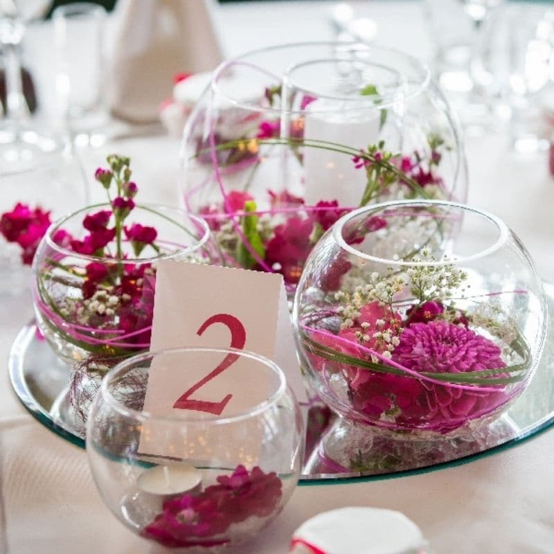 Kugelgläser gefüllt mit Blumen und Kerzen